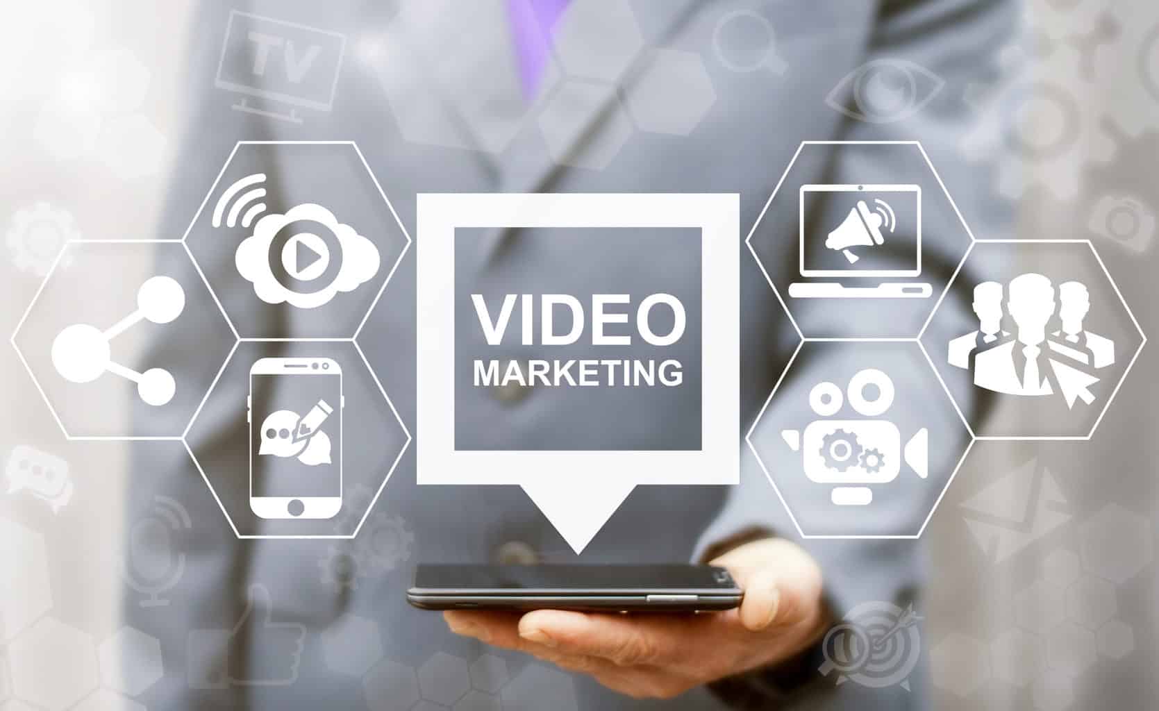 Video Marketing Online Business Mobile concept. Man offers smart phone with video marketing speech bubble icon on a virtual graphical user interface.